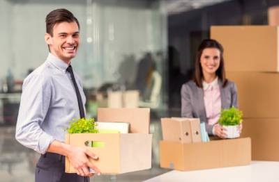 Homme et femme d'entreprise déménageant leurs bureaux remplis de cartons